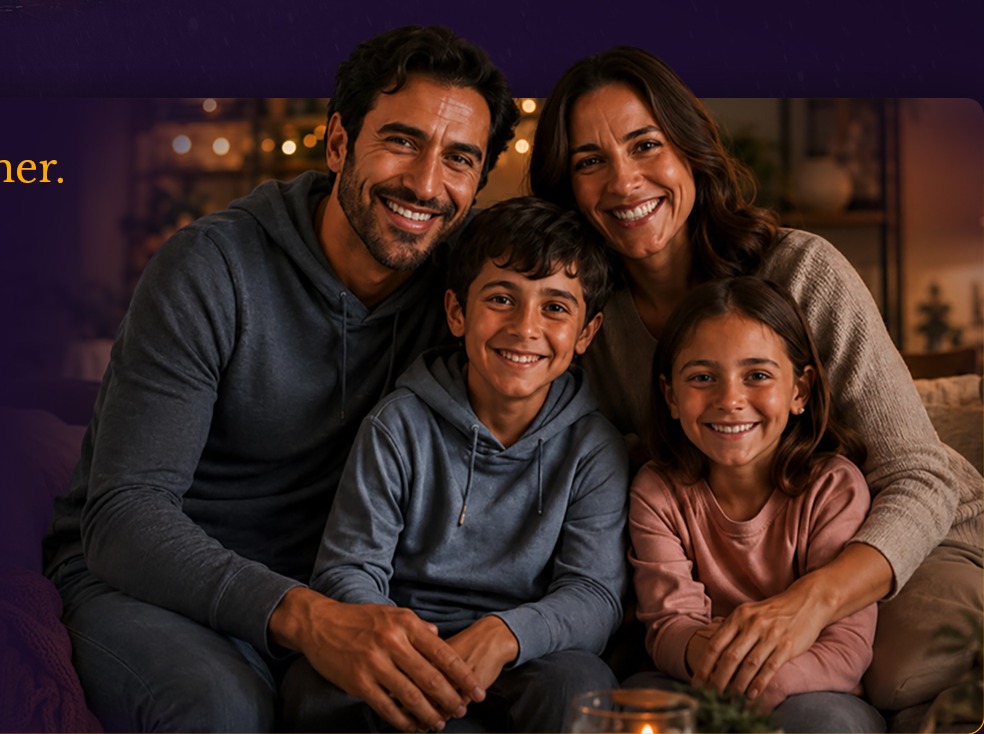A smiling family of four sitting together on a sofa at home